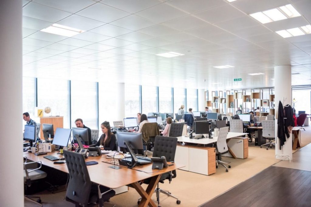 a clean office with employees working on either side and a head table in the middle
