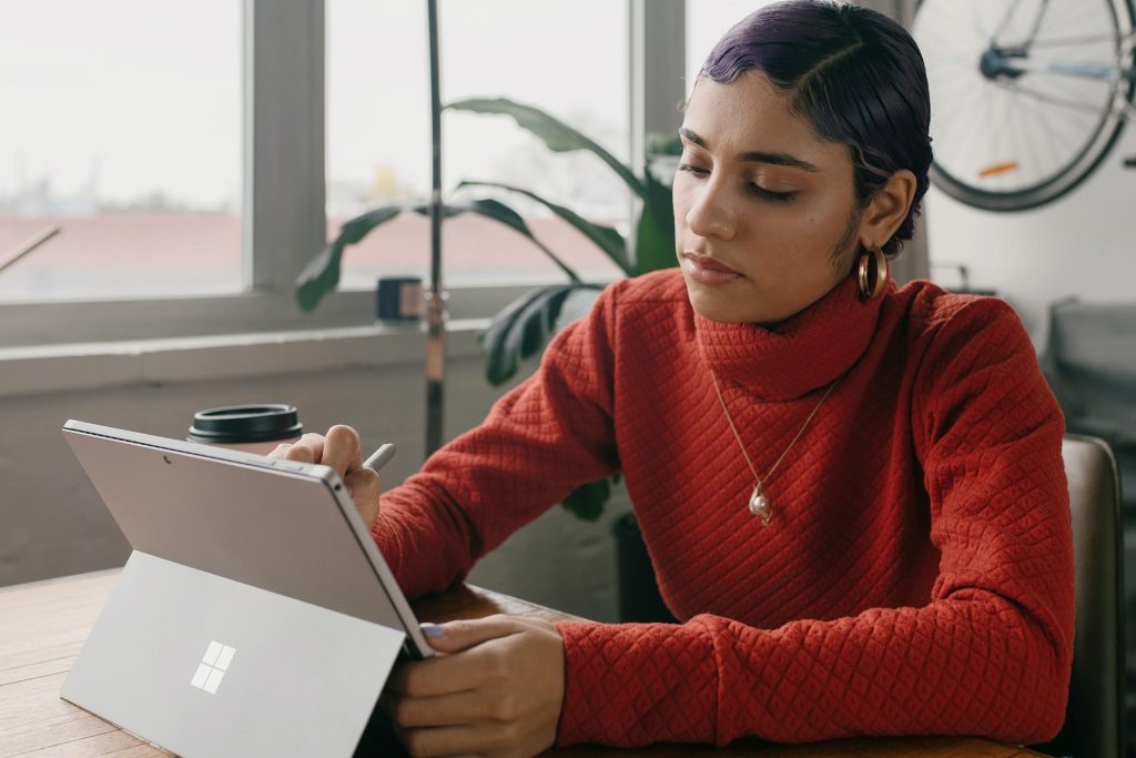 woman focusing on a drawing on the microsoft surface pro while sitting in a clean office