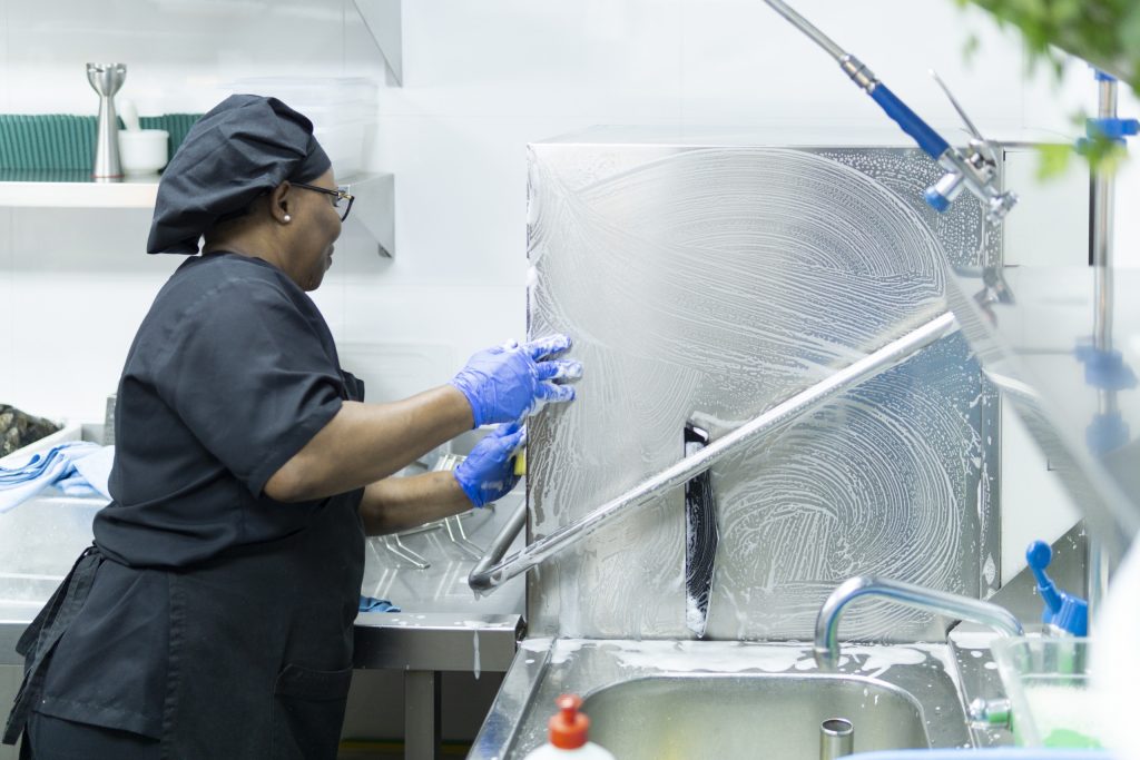 A closeup shot of a hospital cook in black uniform disinfecting hospital kitchen