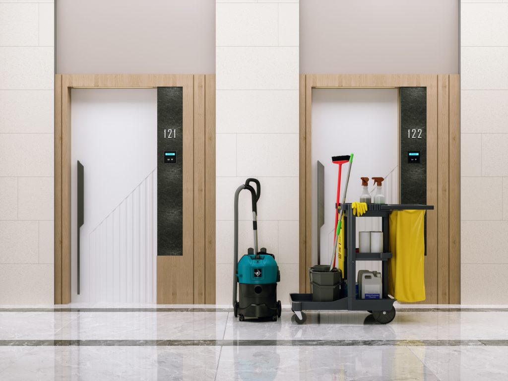 Cleaning Cart With Detergents, Cleaning Mop, Bucket And Vacuum Cleaner In Empty Hotel Corridor